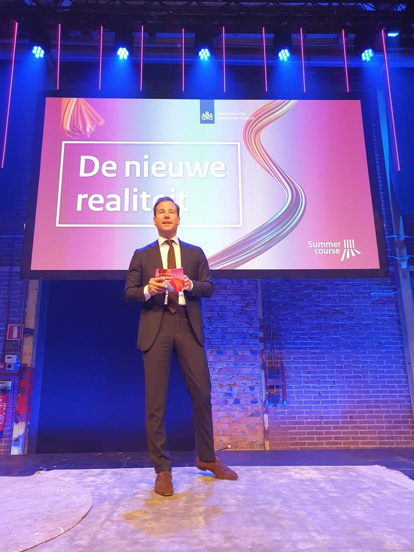 Dagvoorzitter Bart de Jongh staat op het podium van de plenaire zaal in de Fabrique en opent de Summercourse 2024.