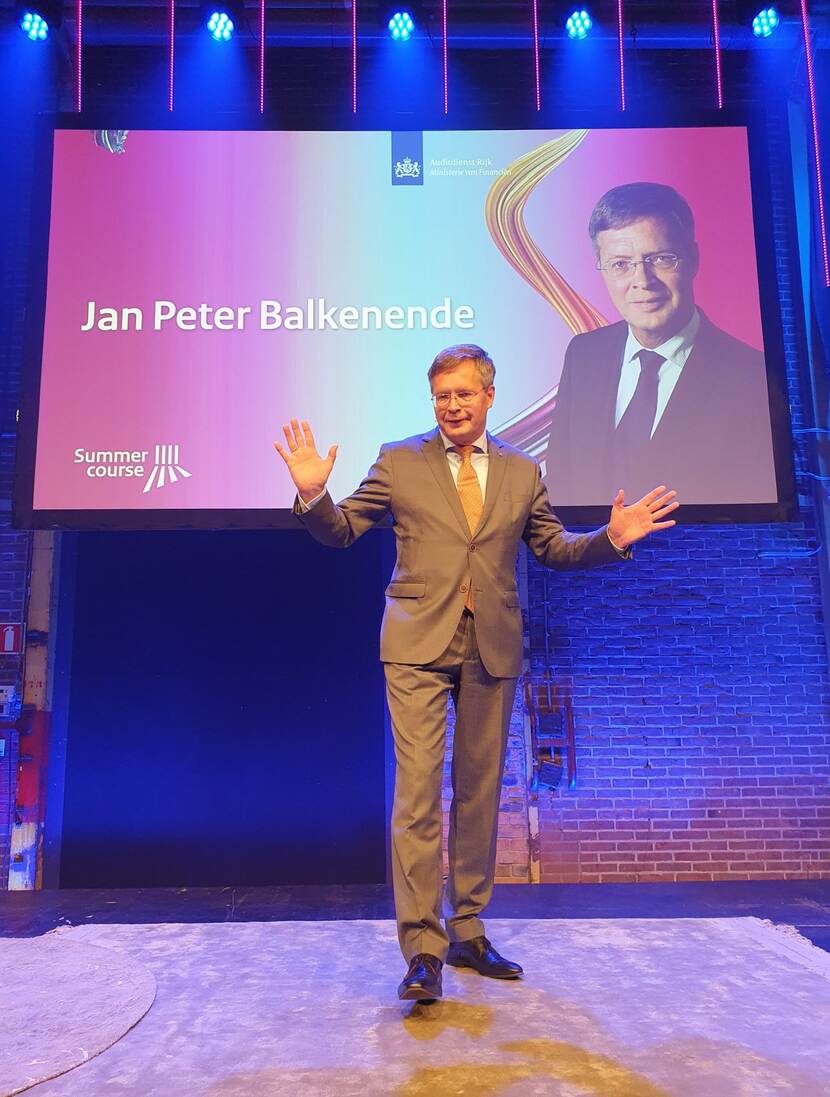 Jan Peter Balkenende opent de dag staandend op het podium en geeft zijn visie op de nieuwe realiteit vanuit verschillende invalshoeken.