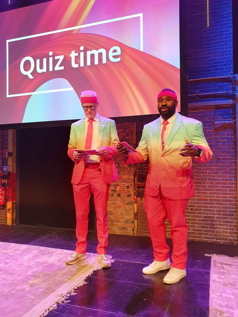 De afsluitende quiz door collega's Hans en Mitchell op het podium in de plenaire zaal.