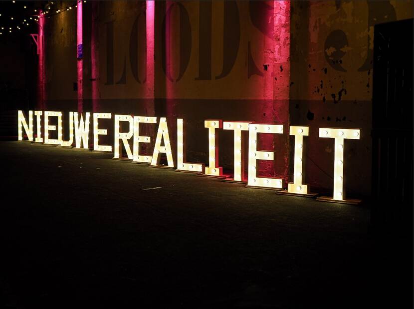 De tekst 'Nieuwe realiteit' in grote lichtletters op de grond van De Fabrique.